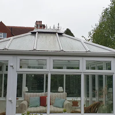 a white glass house with a couch inside of it